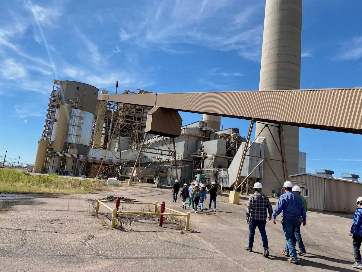 People walking around an industrial structure wearing hard hats